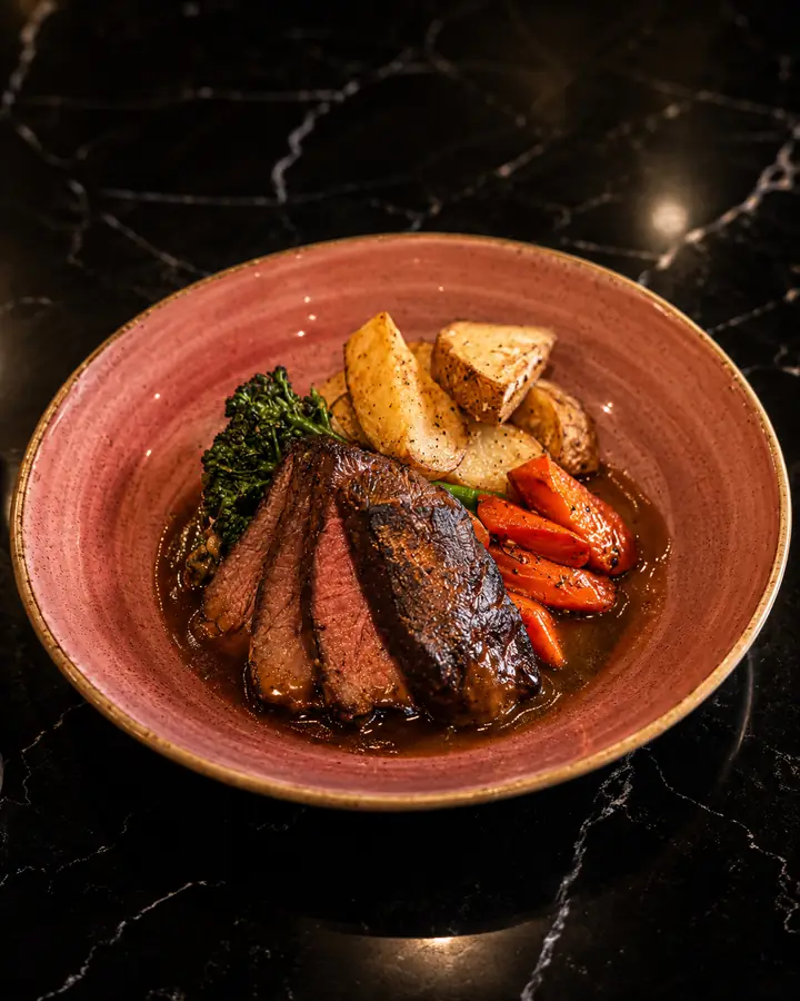 Pomegranate-braised short rib plated with vegetables at MINA